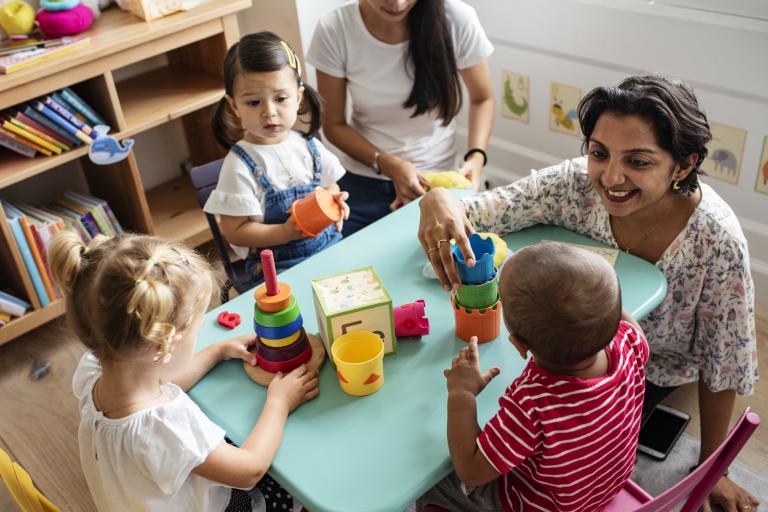 adult with children at a table with toys 