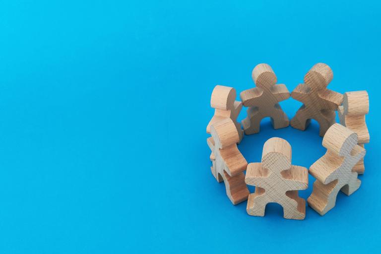 wooden puzzle pieces holding hands in circle with blue background.jpg