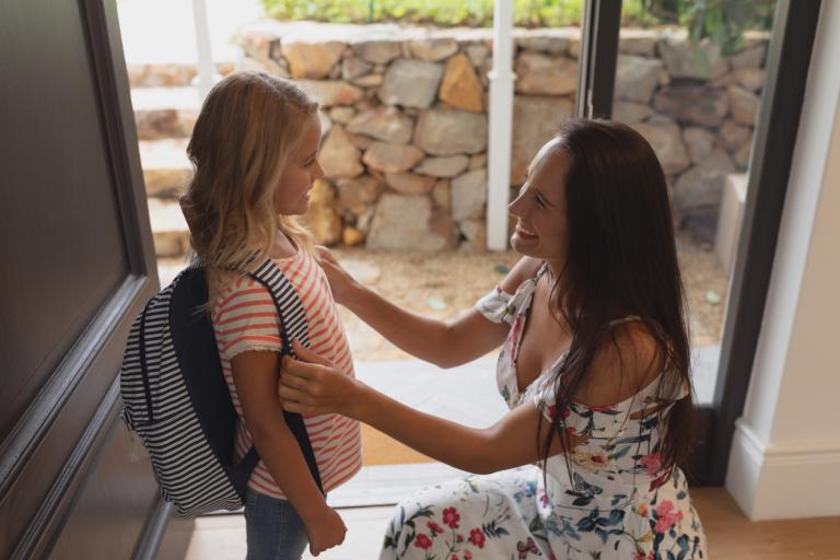 Mother Preparing Her Daughter For School At Home 