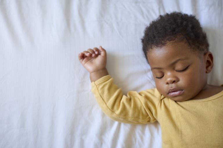 Sleeping Baby Girl Lying On Parents Bed At Home 
