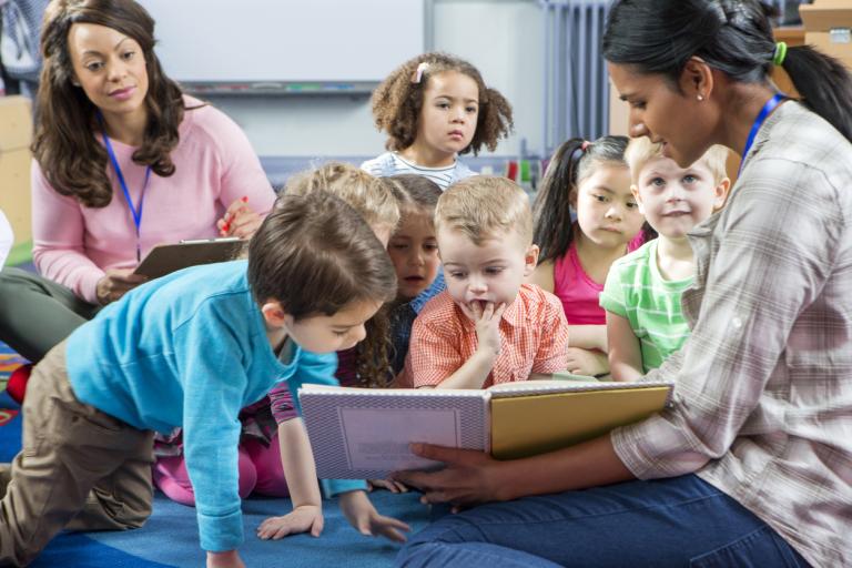 children looking at a book with an adult 